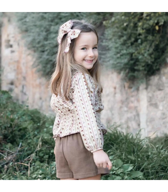 Niña vestida con el Conjunto niña arena algodón blusa floral rayas verticales con falda pantalón lisa reciclada