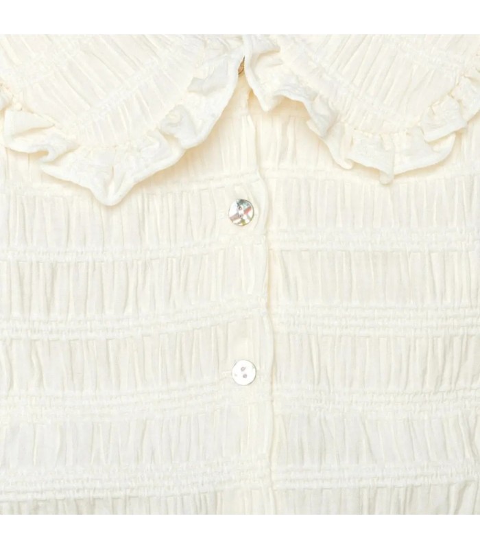 Detalle de textura del conjunto pantalón niña cuadros verde invierno blusa cruda textura labrada cuello volante detalle elegante