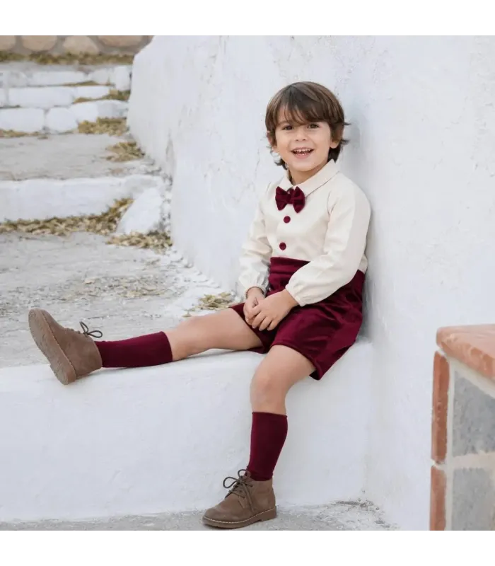 Niño vestido con el conjunto pololo bebé granate elegante con camisa blanca pajarita y pantalón corto tejido suave invierno