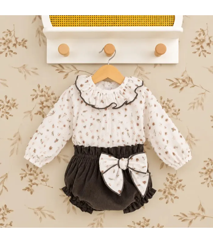 Conjunto bebé navideño con blusa estampada y pololo de pana oscuro. Fondo estudio.
