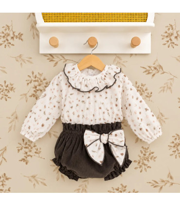 Conjunto bebé navideño con blusa estampada y pololo de pana oscuro. Fondo estudio.