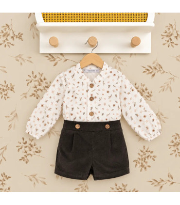 Conjunto bebé navideño con blusa estampada y pololo de pana oscuro. Fondo estudio.