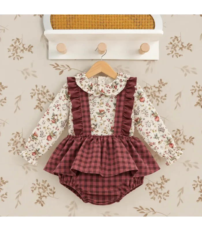 Conjunto bebé Del Sur con blusa floral y peto de cuadros granates. Fondo estudio.