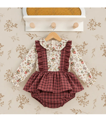 Conjunto bebé Del Sur con blusa floral y peto de cuadros granates. Fondo estudio.