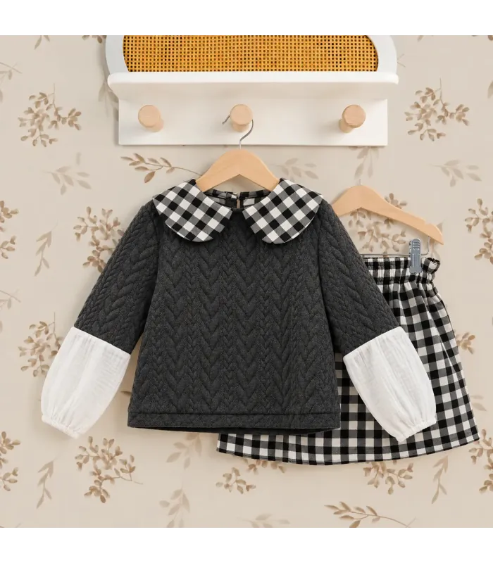 Conjunto Del Sur gris con falda de cuadros blancos y negros. Fondo estudio.
