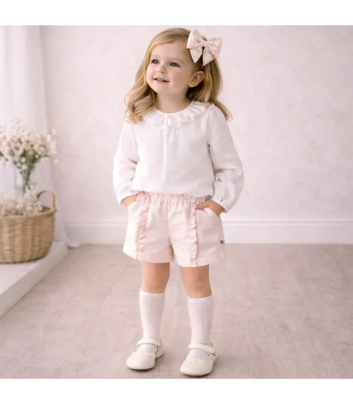 niña con Conjunto Pantalón niña nude con blusa blanca cuello volante y pantalón corto tipo short con volantes laterales algodón