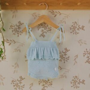 body bebe celeste dulce de fresa primor punto con lazos y volante tejido sobre fondo natural