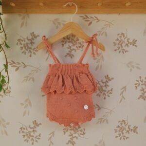 body bebe coral dulce de fresa primor punto con lazos y volante tejido sobre fondo natural